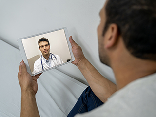 A man looking at his tablet on a telemedicine appointment with his doctor.